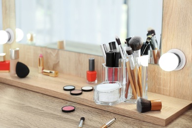 Photo of Organizer with cosmetic products for makeup on table near mirror. Space for text