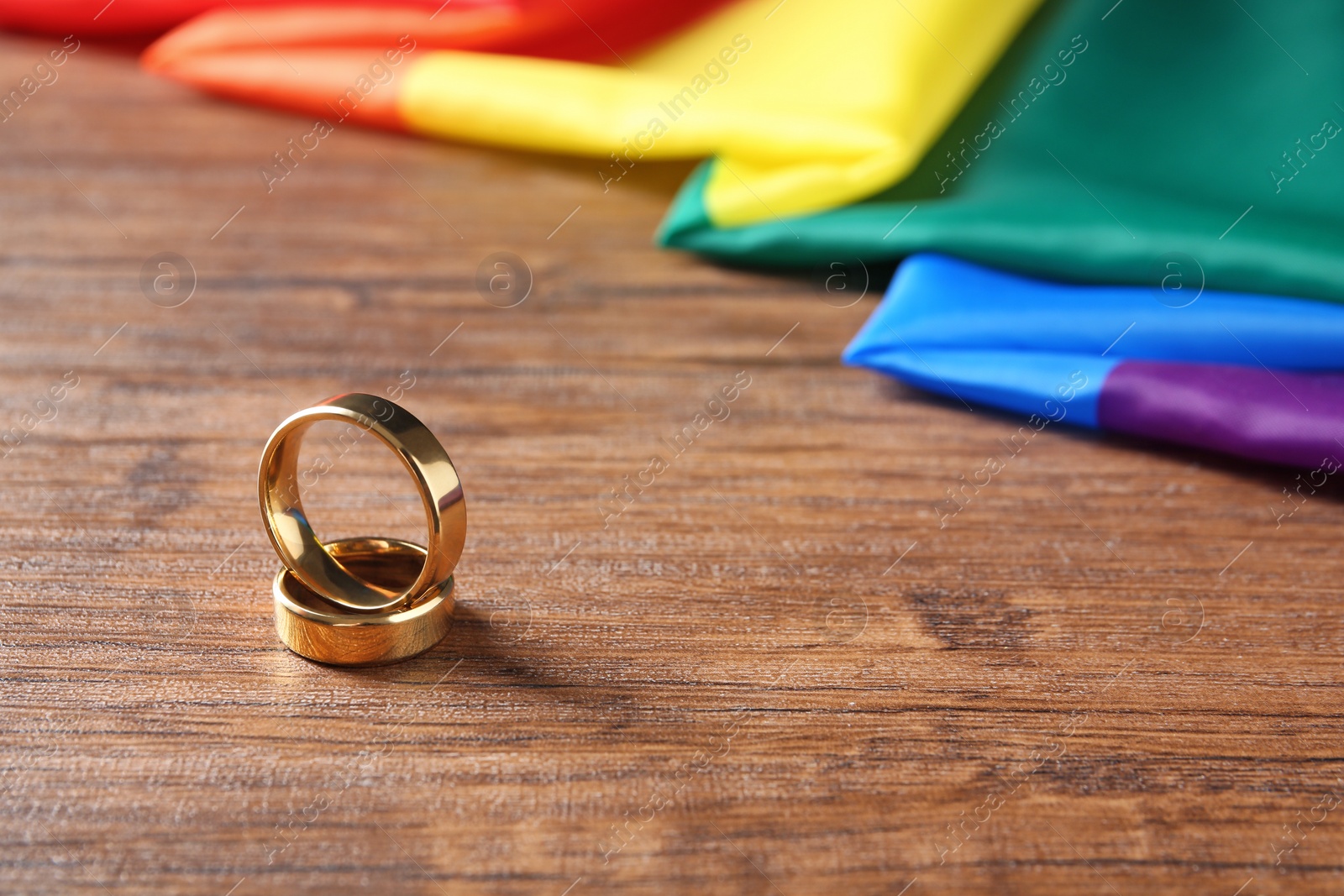 Photo of Wedding rings and rainbow flag on wooden table. Gay marriage