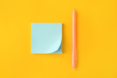 Photo of Blank paper note and pen on orange background, flat lay