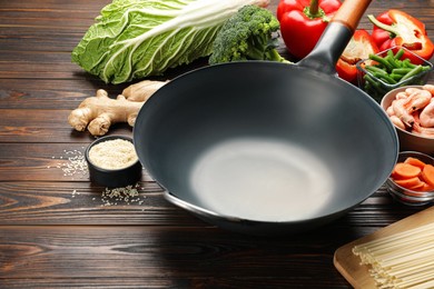 Empty iron wok and raw ingredients on wooden table