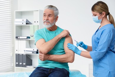 Doctor giving hepatitis vaccine to patient in clinic