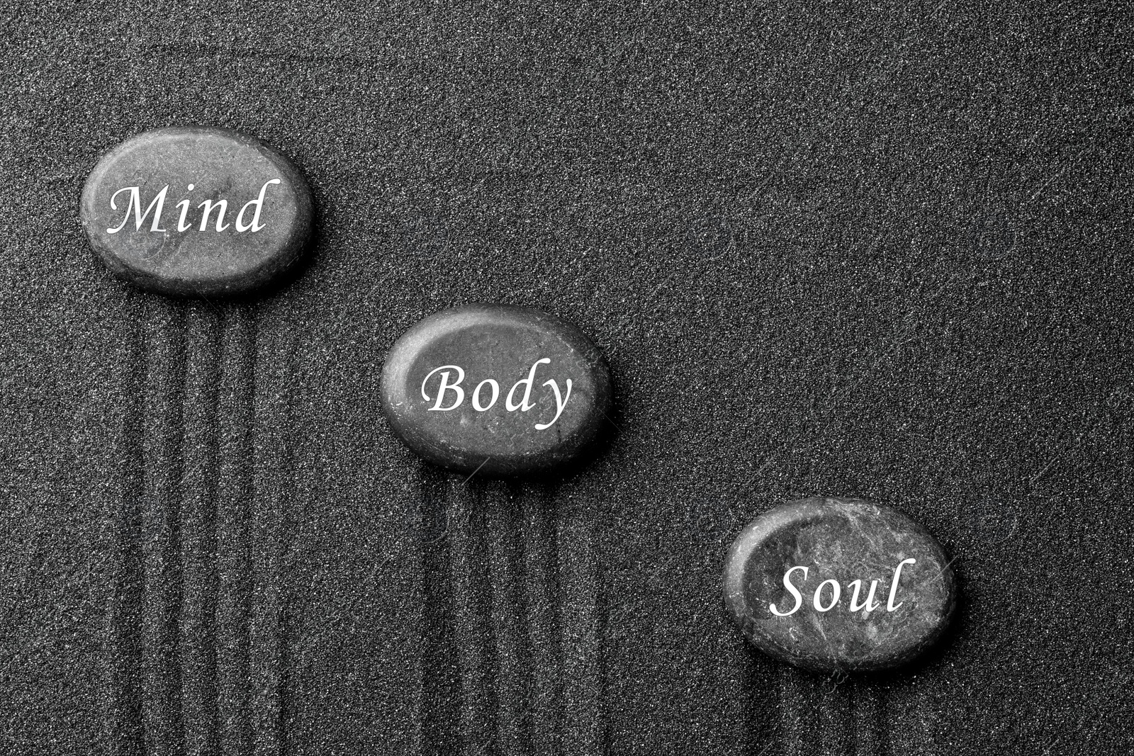 Image of Stones with words Mind, Body, Soul on sand, flat lay. Zen and harmony 