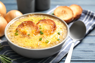 Photo of Tasty homemade french onion soup served on blue wooden table