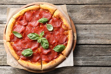 Tasty pepperoni pizza with basil on wooden table, top view. Space for text