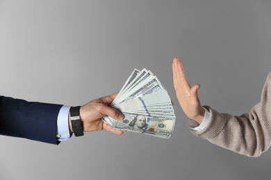 Woman refusing to take bribe on grey background, closeup of hands