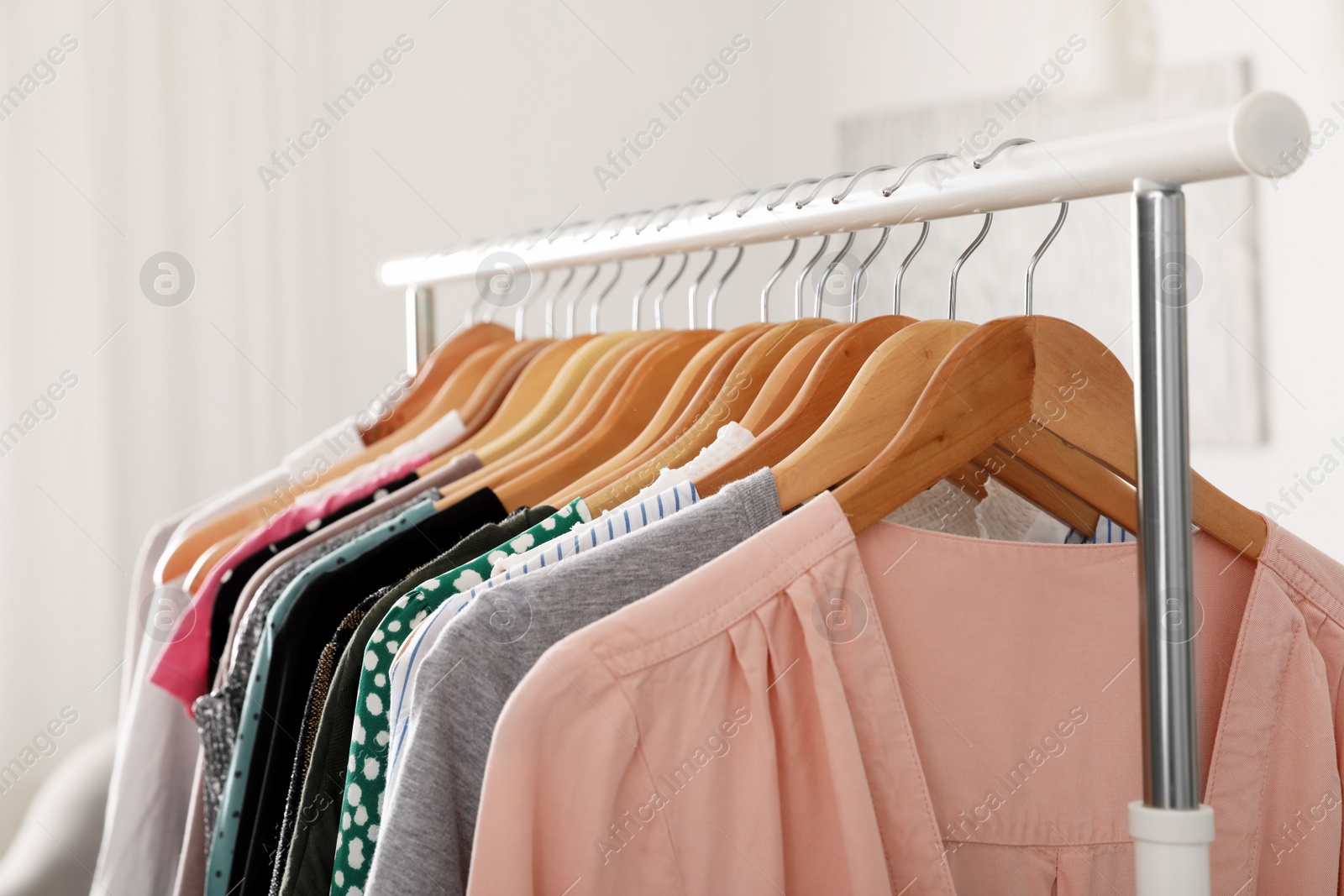 Photo of Wardrobe rack with stylish clothes indoors, closeup