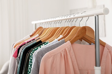Photo of Wardrobe rack with stylish clothes indoors, closeup
