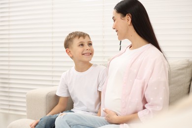 Happy pregnant woman spending time with her son at home