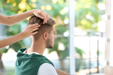 Professional hairdresser working with young man in barbershop. Trendy hair color