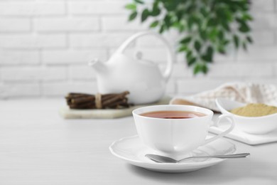 Photo of Aromatic licorice tea in cup served on white table, space for text