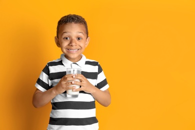 Photo of Adorable African-American boy with glass of milk on color background