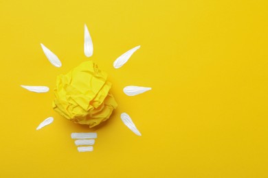 Composition with crumpled paper ball as lamp bulb on yellow background, top view and space for text. Idea concept