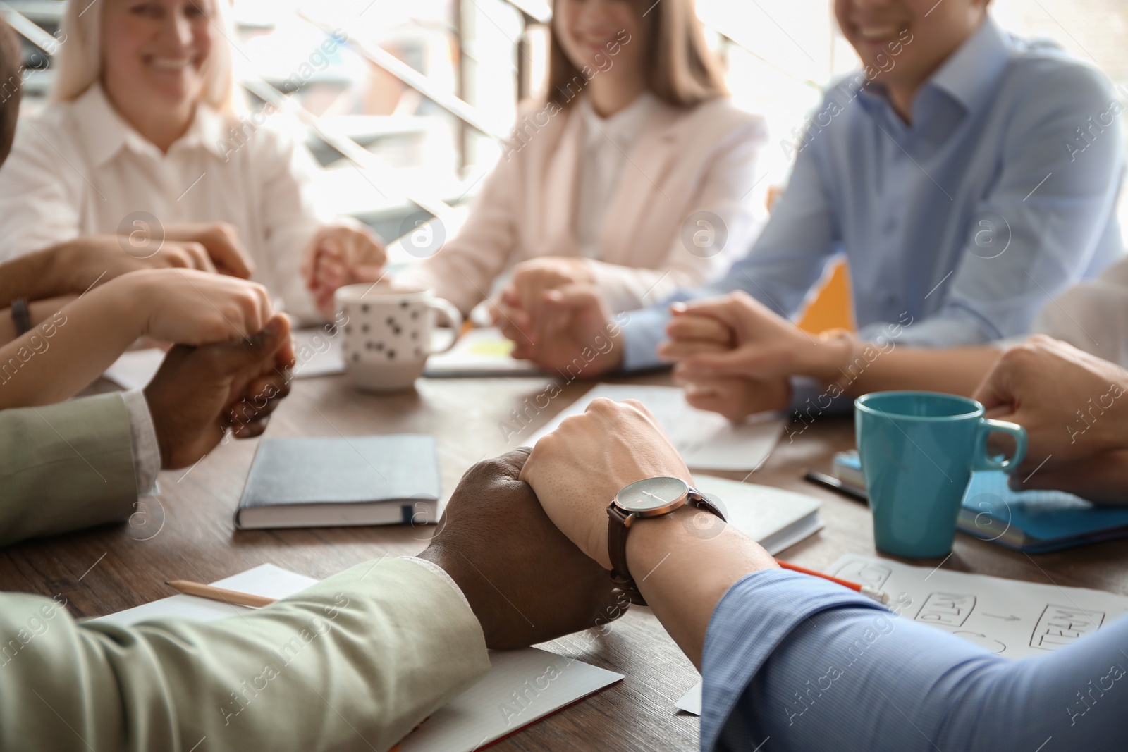 Photo of People holding hands together at table. Unity concept