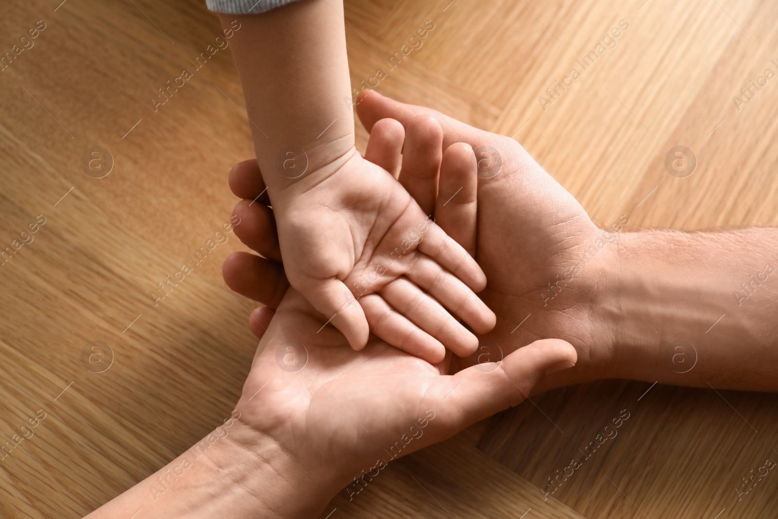 Photo of Happy family holding hands on wooden background, closeup