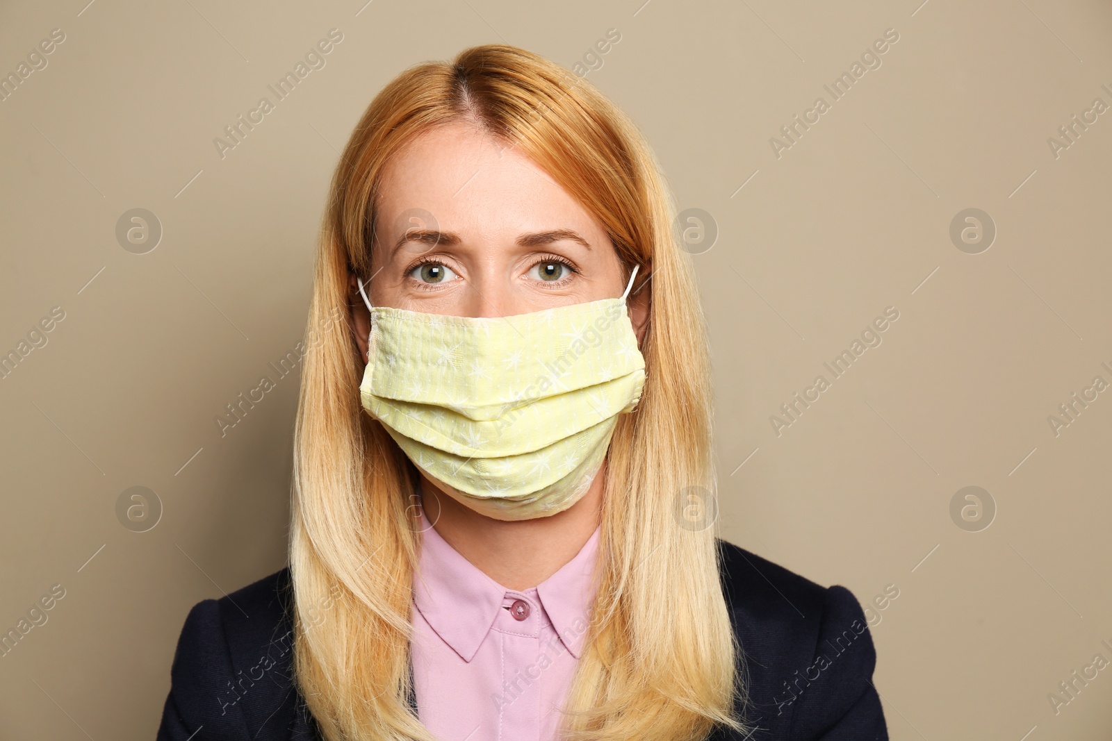 Photo of Woman wearing handmade cloth mask on beige background. Personal protective equipment during COVID-19 pandemic