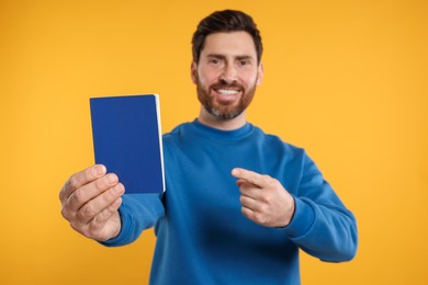 Photo of Immigration. Happy man with passport on orange background, selective focus