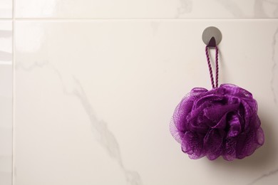 Photo of Purple shower puff hanging in bathroom, space for text