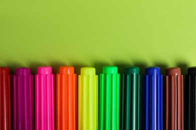 Photo of Set of felt tip pens on light green background, flat lay