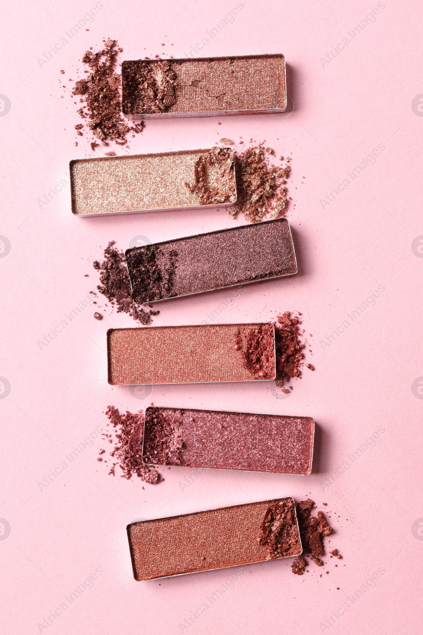 Photo of Different crushed eye shadows on pink background, flat lay. Professional makeup product