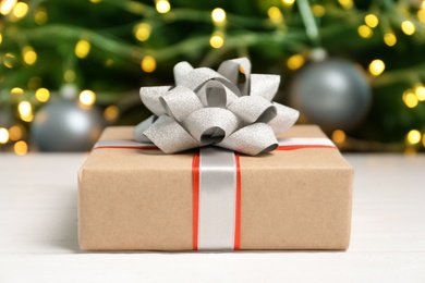 Photo of Beautiful gift box and blurred Christmas tree on background