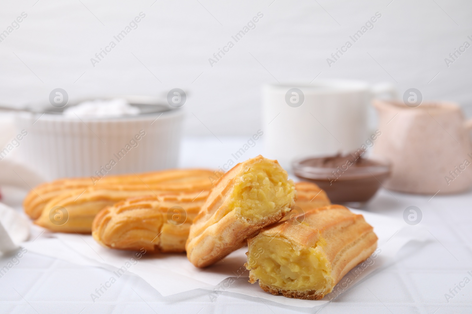 Photo of Delicious eclairs on white checkered table, closeup view
