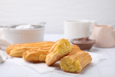 Delicious eclairs on white checkered table, closeup view