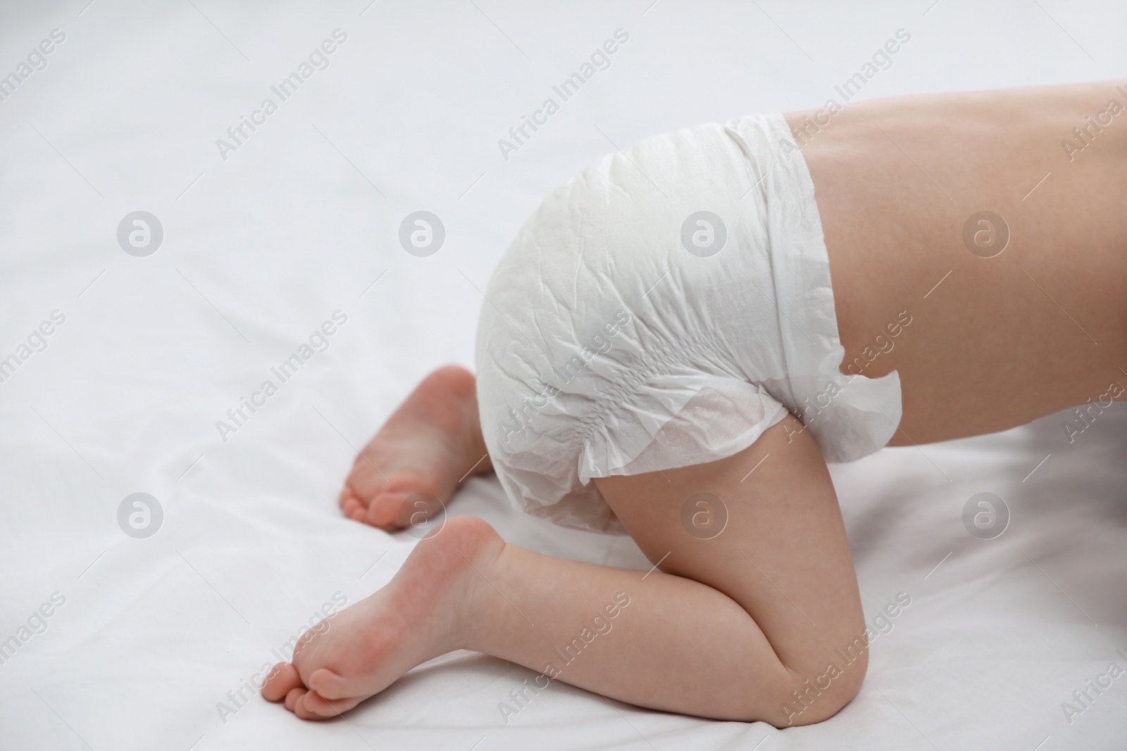 Photo of Cute little baby in diaper on bed, closeup