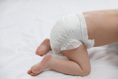 Cute little baby in diaper on bed, closeup