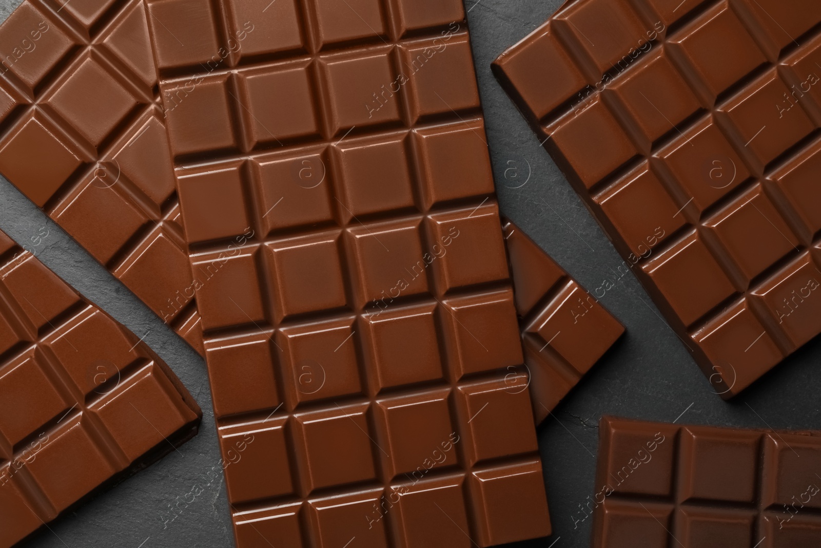 Photo of Pieces of tasty chocolate bars on grey table, flat lay