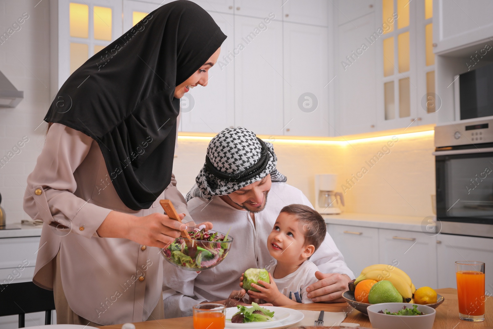 Photo of Happy Muslim family eating together in kitchen