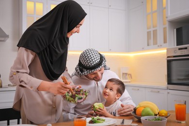 Happy Muslim family eating together in kitchen