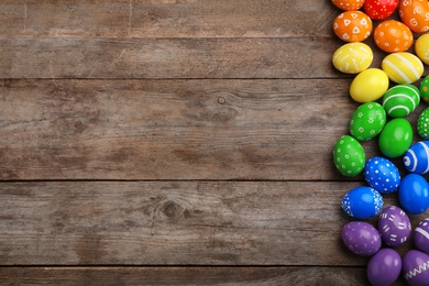 Photo of Decorated Easter eggs and space for text on wooden background, top view