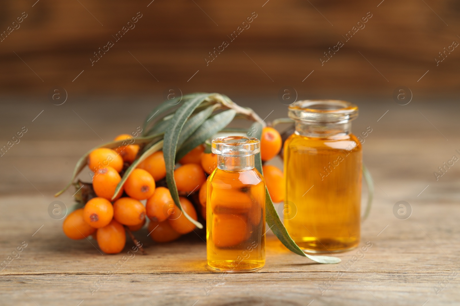 Photo of Natural sea buckthorn oil and fresh berries on wooden table