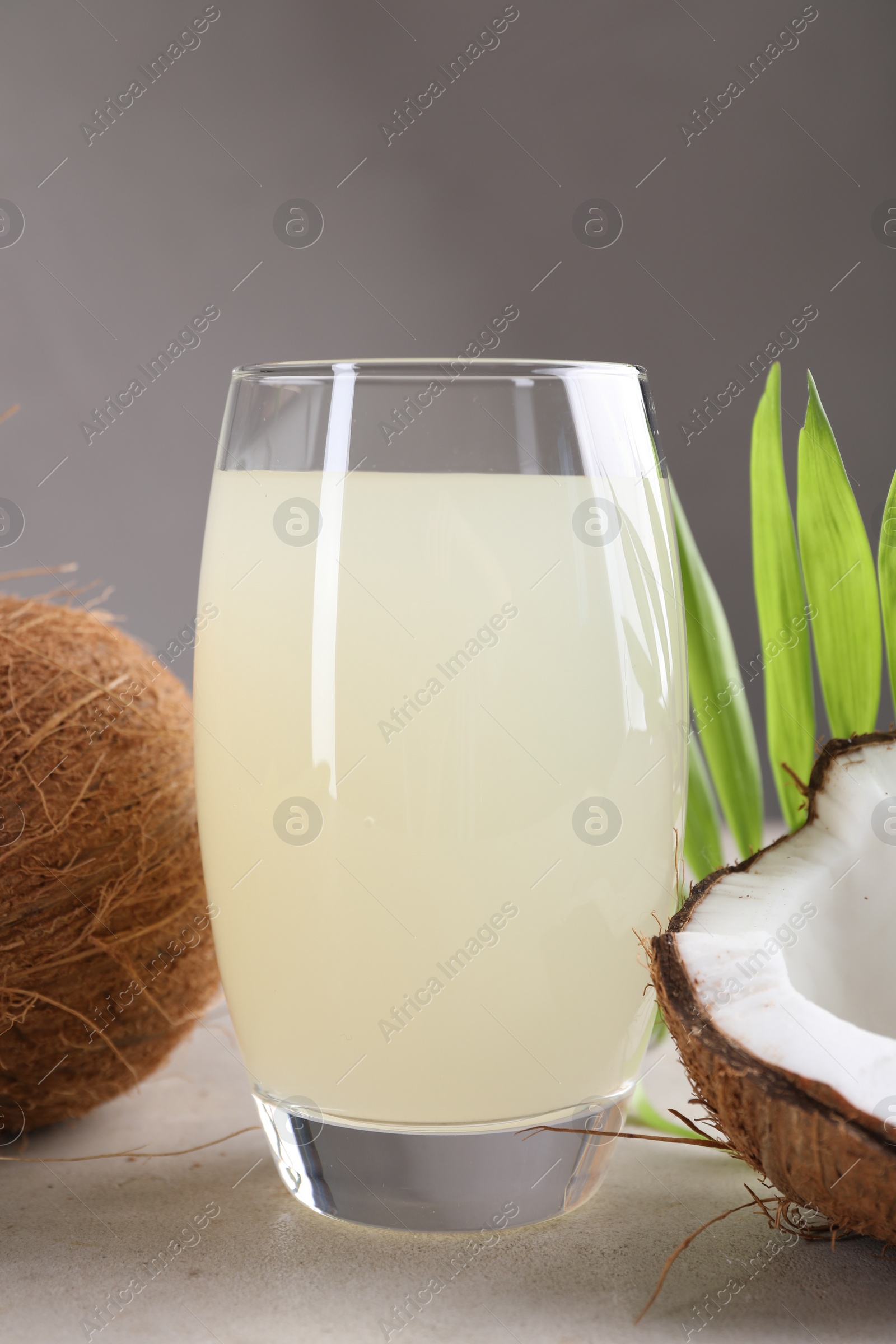 Photo of Glass of coconut water, palm leaves and nuts on light table