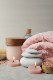 Beautiful composition with burning candles and different spa products on light grey table