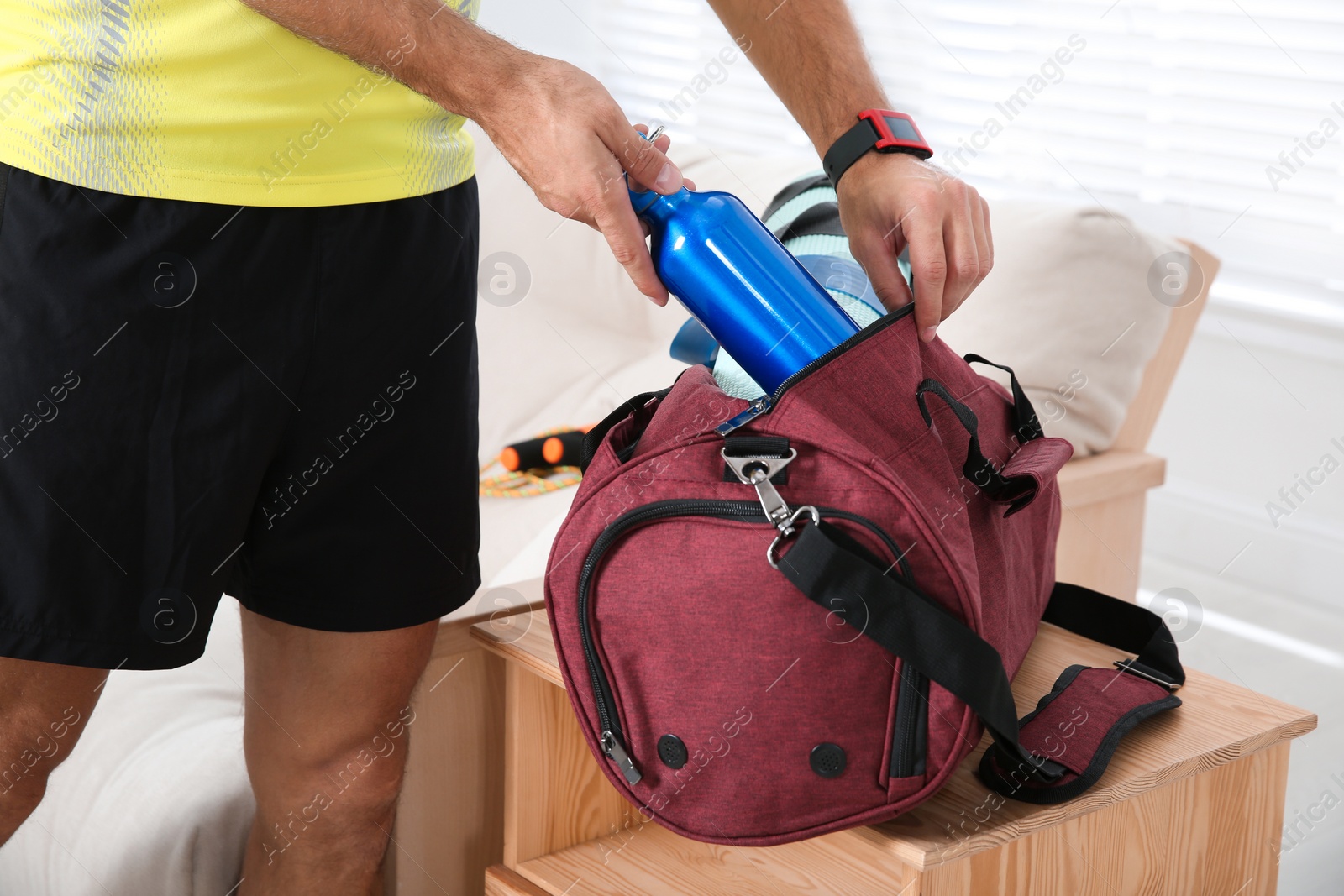 Photo of Man packing sports stuff for training into bag at home, closeup