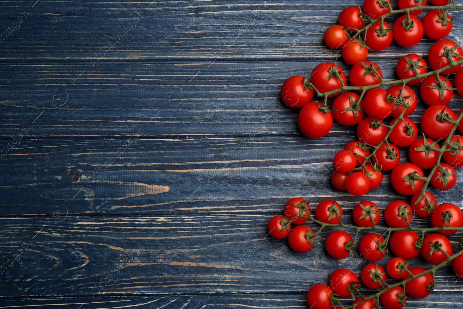 Photo of Fresh ripe cherry tomatoes on blue wooden table, flat lay. Space for text