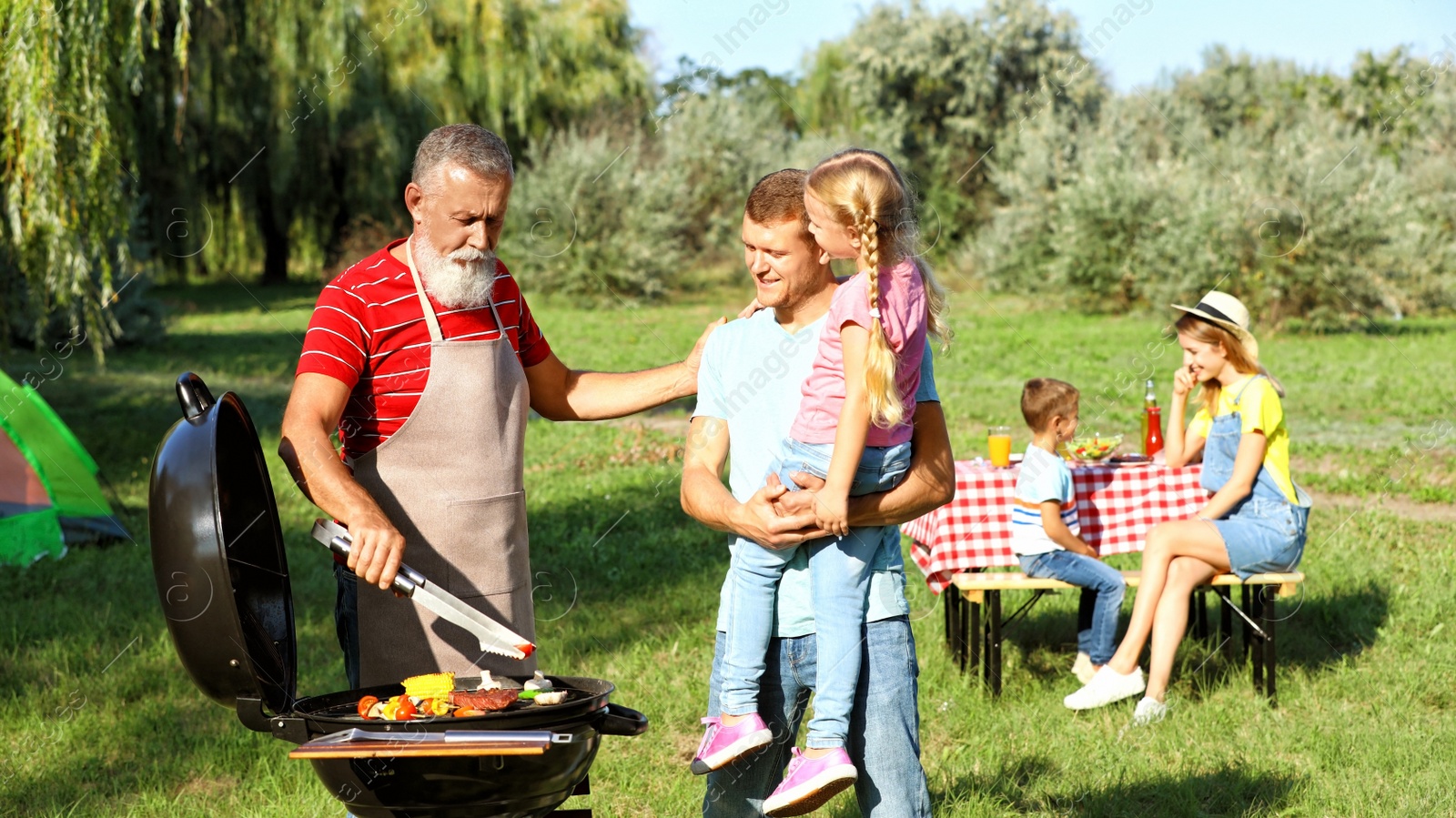 Photo of Happy family having barbecue in park on sunny day