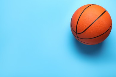 Photo of Orange ball on light blue background, top view with space for text. Basketball equipment