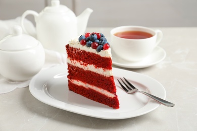 Photo of Plate with piece of delicious homemade red velvet cake on table