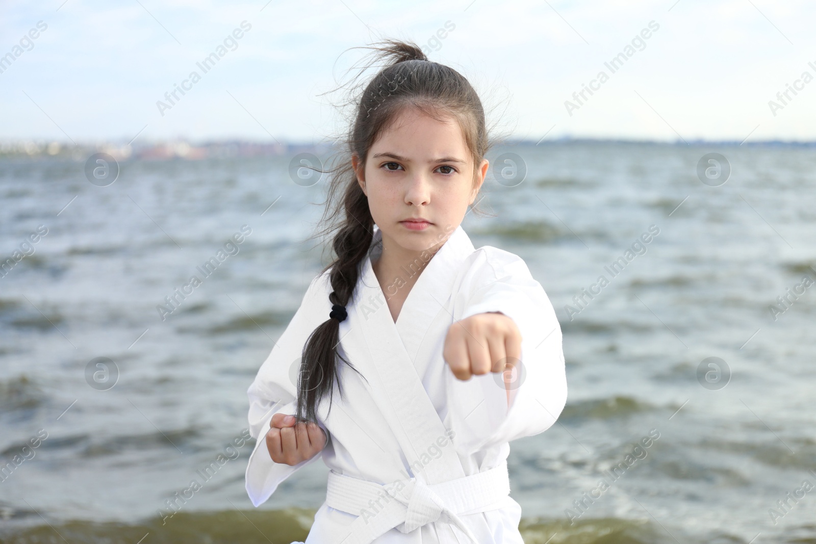 Photo of Cute little girl in kimono practicing karate near river
