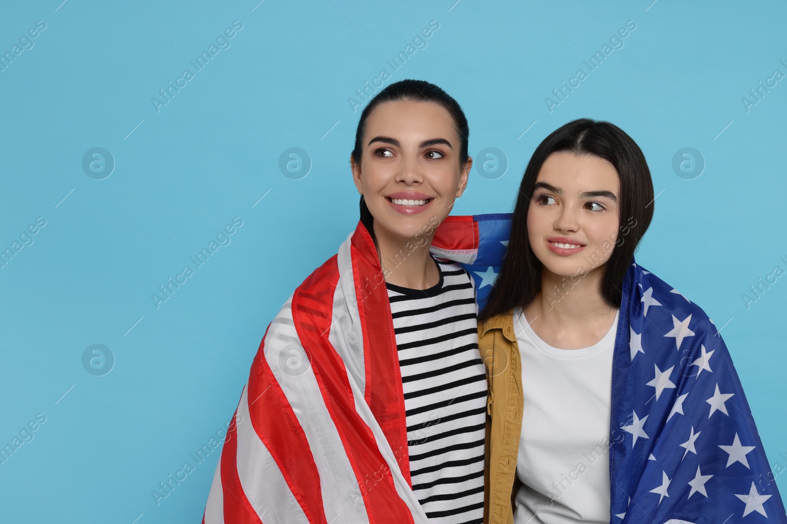 Photo of 4th of July - Independence Day of USA. Happy woman and her daughter with American flag on light blue background, space for text