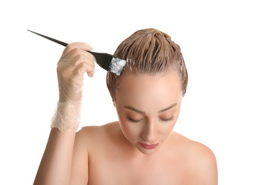 Young woman dyeing her hair against white background