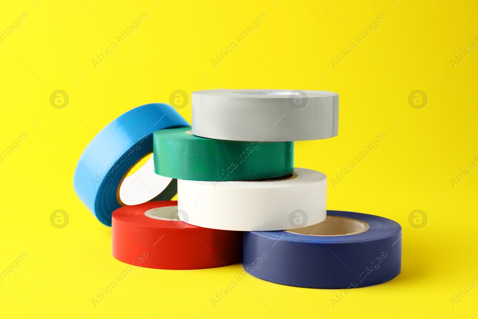 Photo of Colorful insulating tapes on yellow background. Electrician's supplies