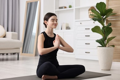 Photo of Beautiful girl meditating on yoga mat at home
