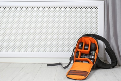 Bag with digital camera on floor indoors. Professional photographer's equipment