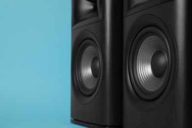 Wooden sound speakers on light blue background, closeup. Space for text
