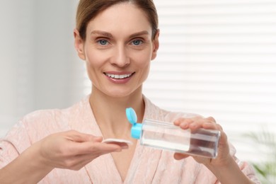 Photo of Beautiful woman with makeup remover and cotton pad indoors