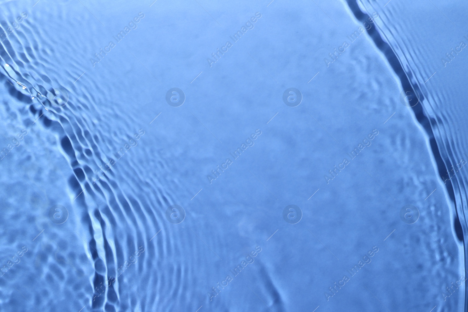 Image of Rippled surface of clear water on light blue background, closeup