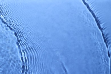 Rippled surface of clear water on light blue background, closeup